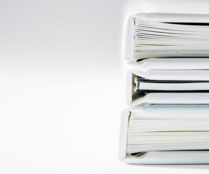 A stack of thick folders on a white surface